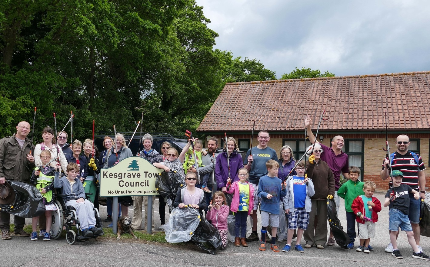 A large group of Kesgrave residents of all ages standing together outside the Town Council office, holding litter pickers and bin bags, ready to participate in a community clean-up event.