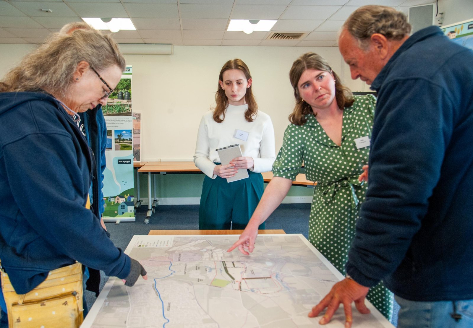 Residents discussing development plans at a consultation event, pointing to a large map showing the proposed Bloor Homes site at Foxhall Road near Kesgrave.